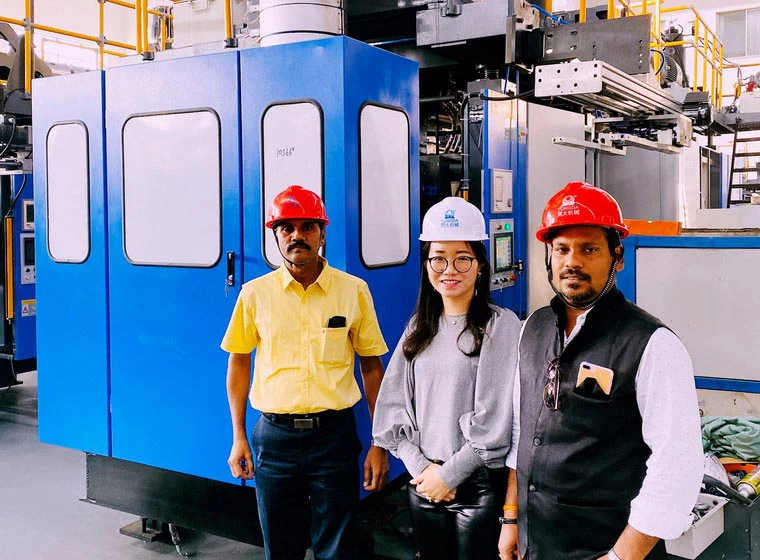 Three visitors beside a blue machine