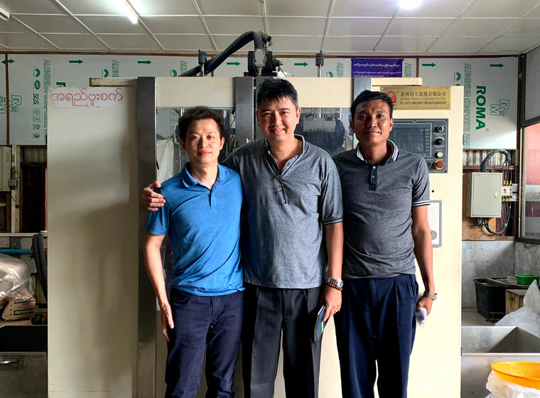 Three visitors beside production equipment